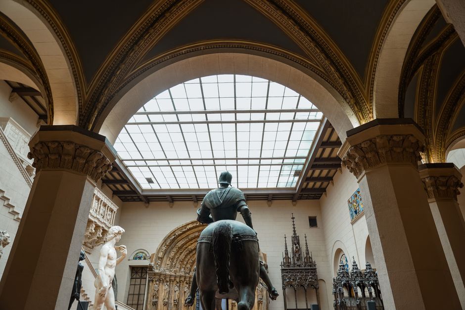 Back view of sculptures in a museum with intricate architectural details and arched ceilin
