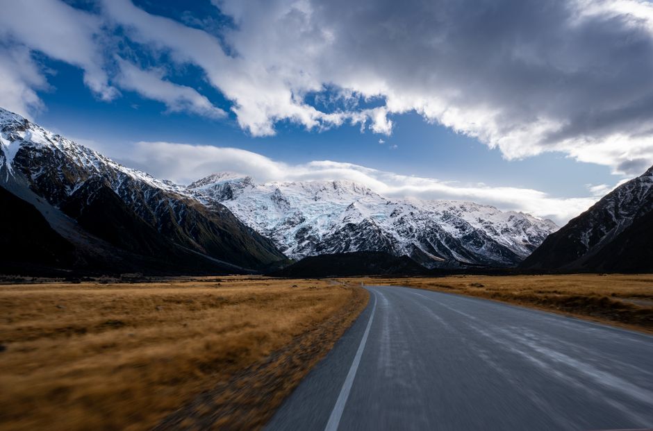 Breathtaking view of Aoraki Mount Cook with a scenic road in New Zealand. Clear skies and snow-capped peaks.