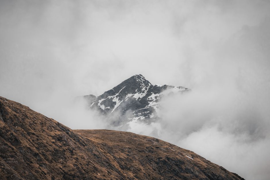 A captivating view of a snow-capped mountain peak shrouded in mist and clouds, evoking mystery and tranquility.