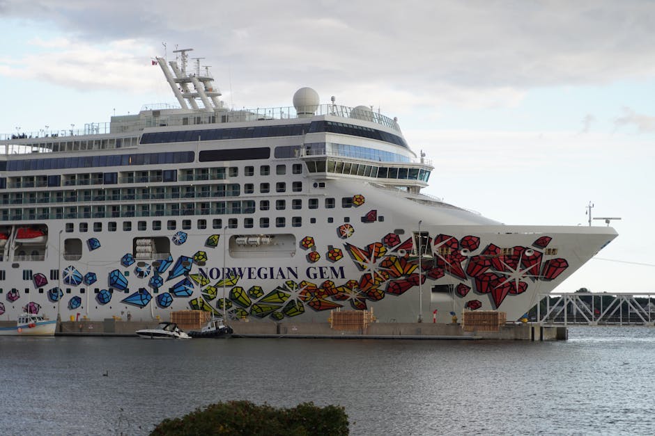 Norwegian Gem cruise ship docked with artistic hull design in port.
