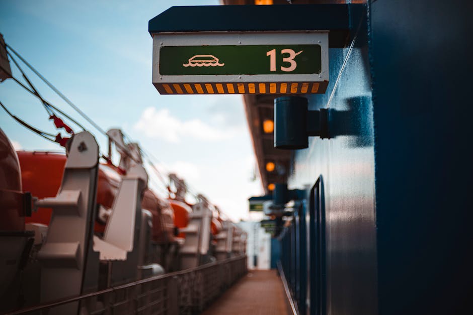 Close-up of a ship deck showing a green sign with a lifeboat symbol and the number 13.