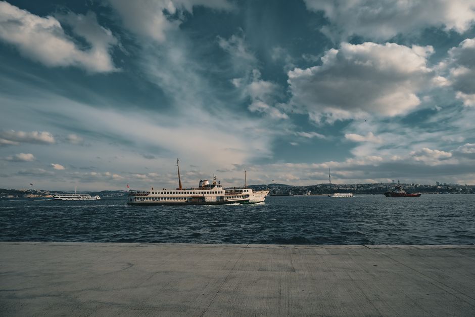 A ferry navigates the Bosphorus Strait under a vibrant sky, capturing Istanbul's urban skyline.
