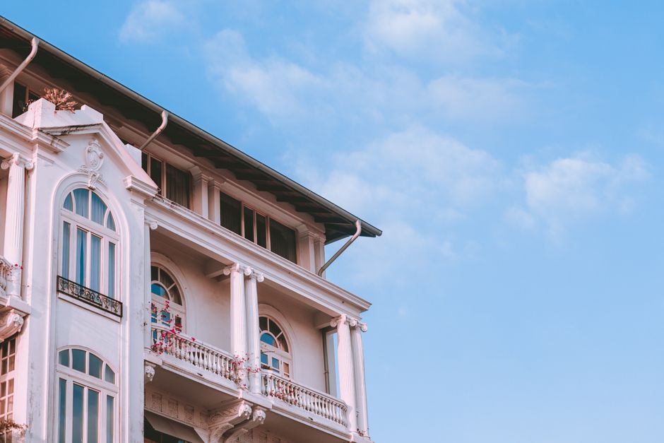 A charming neoclassical building facade against a vibrant blue sky, showcasing architectural elegance.