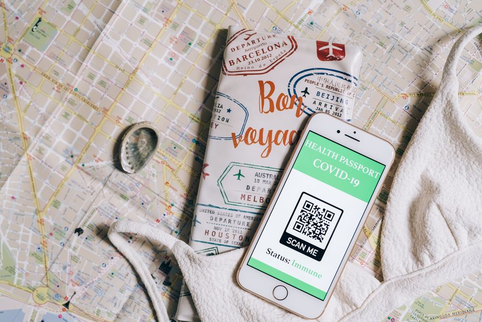 Smartphone displaying a health passport with QR code on a travel map and passport cover.