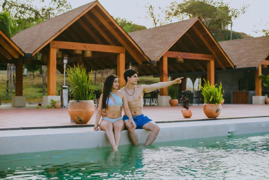 Young couple enjoying sunny day by the pool at a resort, soaking in tranquility.
