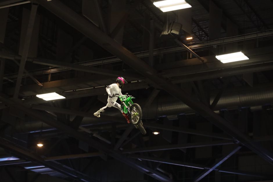 A skilled motocross rider performs a daring stunt indoors.
