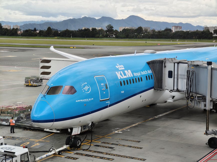 KLM airplane at boarding gate in Bogotá airport with mountain backdrop, ready for departure.