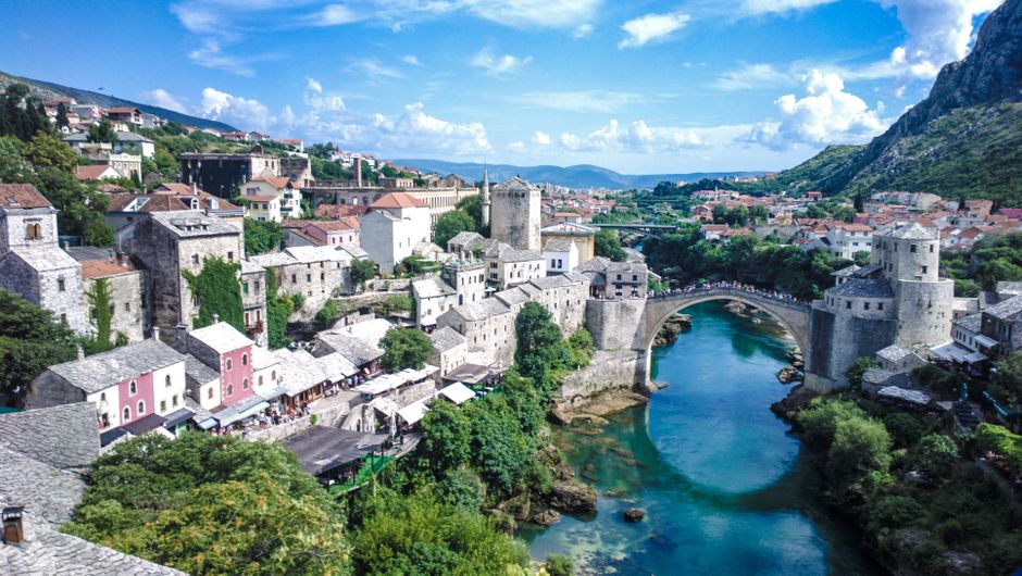 Scenic view of the iconic Old Bridge in Mostar, showcasing medieval architecture and vibrant surroundings.