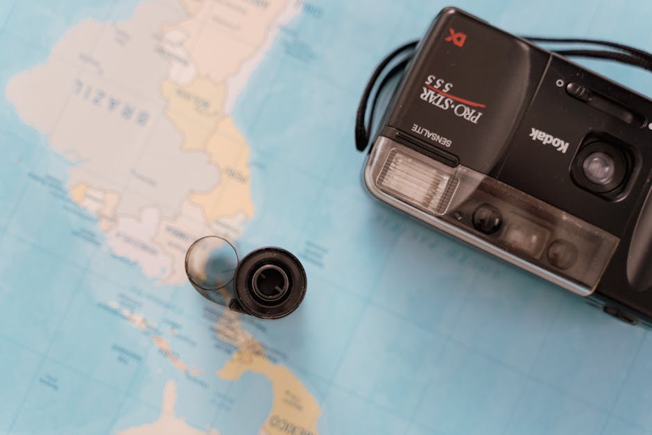 Film camera on world map, symbolizing travel and exploration.