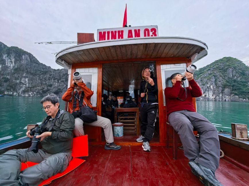 Photographers on a boat capturing the stunning landscapes of Halong Bay.