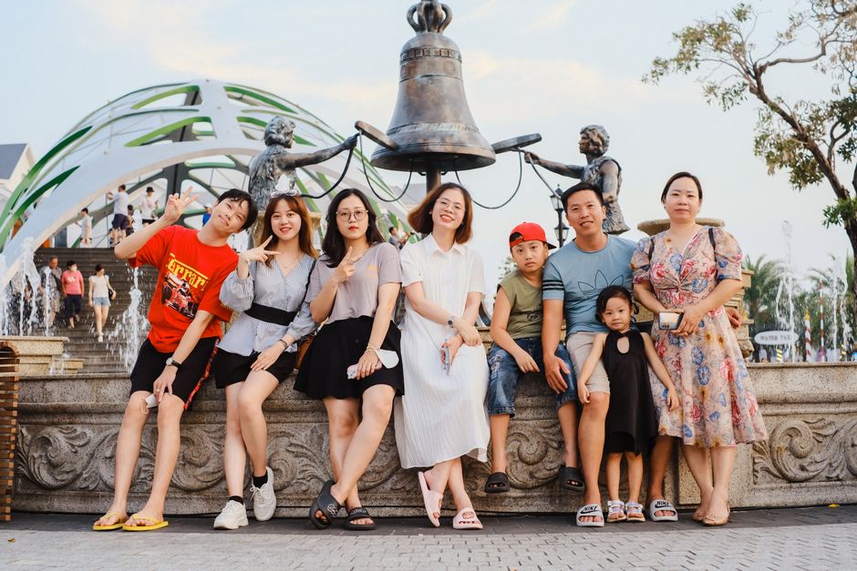 Joyful family group posing by a decorative city fountain in daylight.