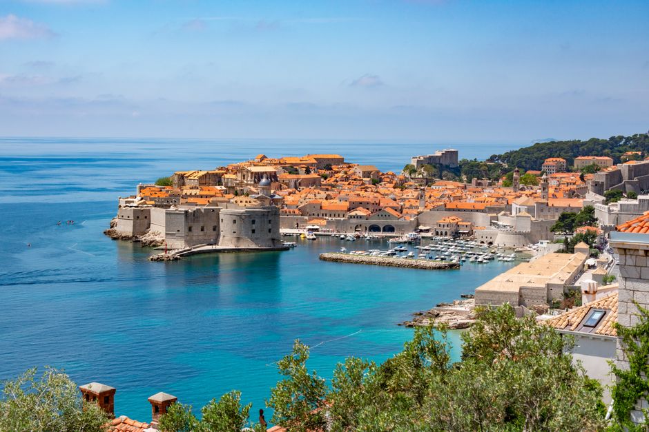 Panoramic view of Dubrovnik's historic old town and harbor on a sunny summer day.