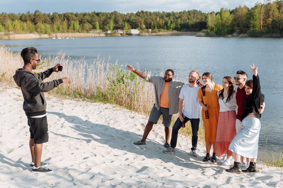 Friends posing for a photo on a sunny day by the lake, enjoying leisure time together.