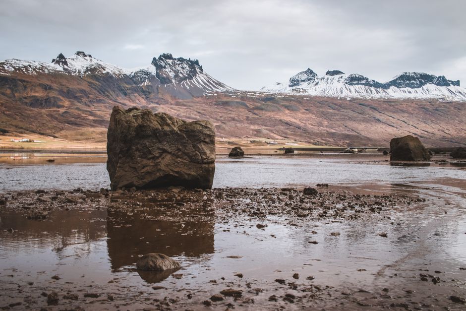 A stunning view of Iceland's rugged terrain and snow-capped peaks under a cloudy sky.