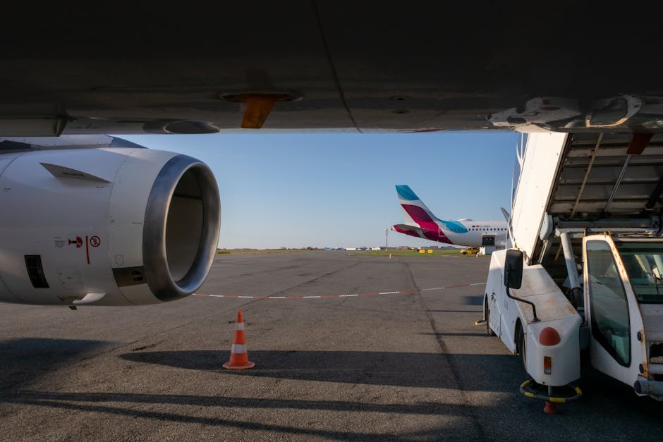 View of airplane turbine and jet bridge at airport with clear skies.